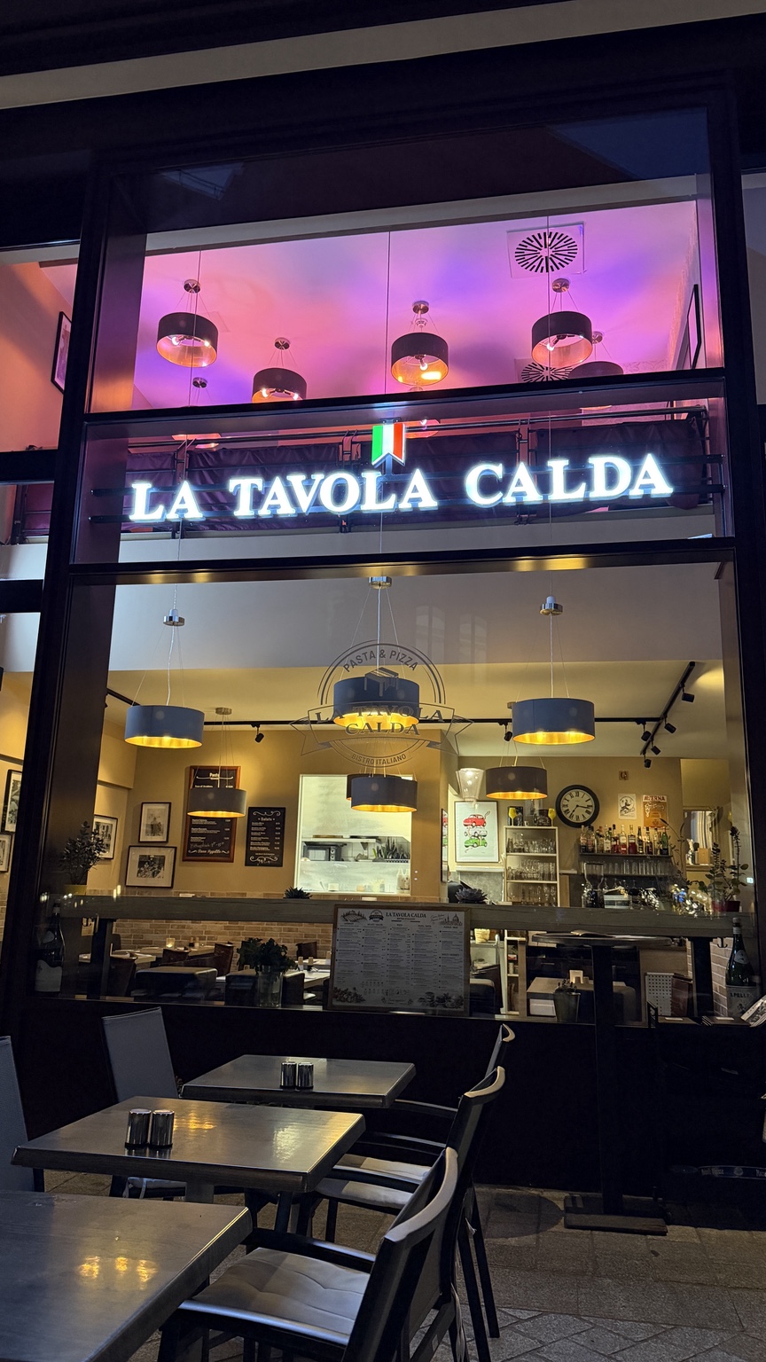 Beleuchteter Eingang von La Tavola Calda am Abend